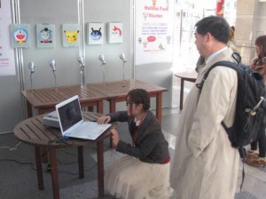 (3) 学長先生が!スクリーンに投影された動く視覚刺激がどう見えるか体験していただいています。 (3) 学長先生が!スクリーンに投影された動く視覚刺激がどう見えるか体験していただいています。